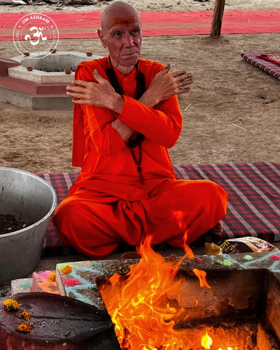 Swami Yogesh Puri jI praying with crossed arms at the fire.